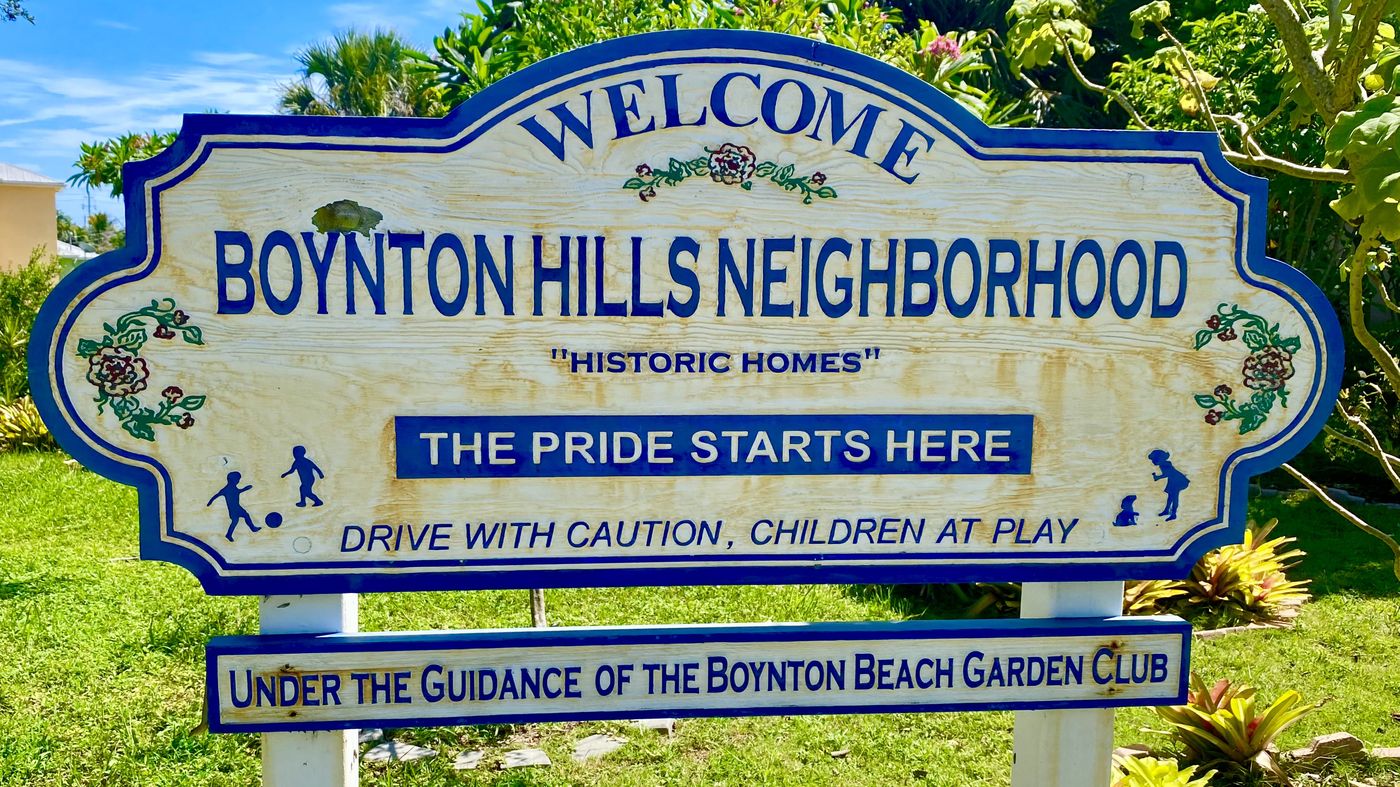 Welcome sign at the Boynton Hills Neighborhood, reading The Pride Starts Here, with a plank below noting the neighborhood is under the guidance of the Boynton Beach Garden Club